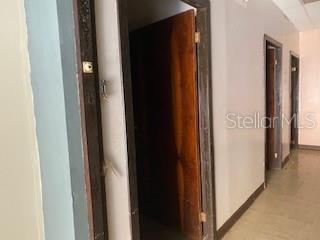 A hallway with light-colored walls and tile flooring features several wooden doors — 26 CORCHADO, AGUADILLA, PR