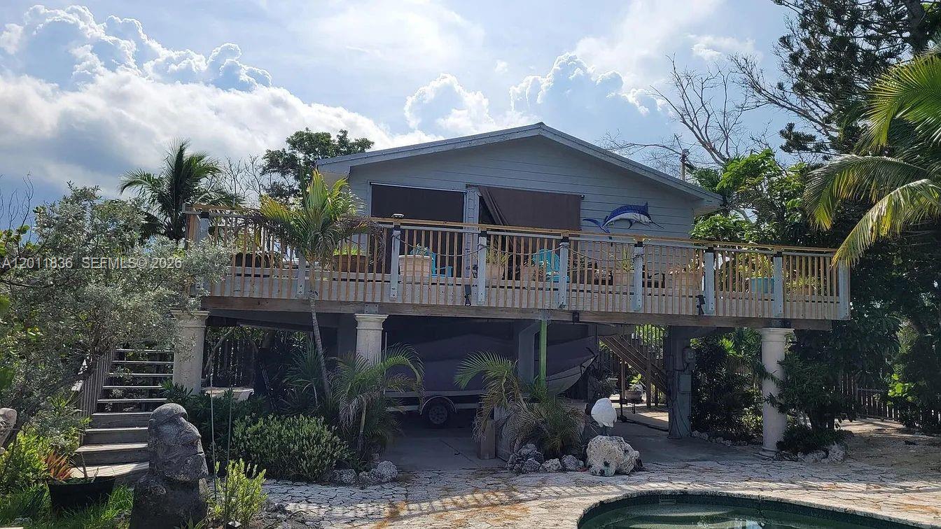 An elevated house with a wooden deck, a boat parked underneath, and a swimming pool — 167 Valois Blvd, Key Largo FL 33037, KEY LARGO, FL