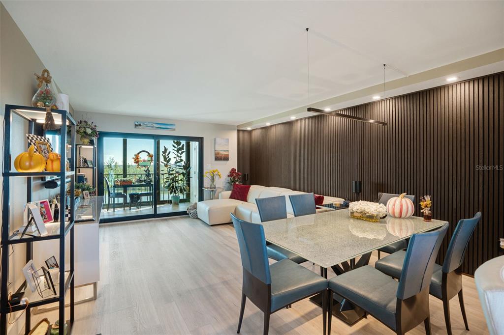 A dining and living area features a slatted wood accent wall and a glass-topped table — 9397 MIDNIGHT PASS ROAD UNIT 905, SARASOTA, FL