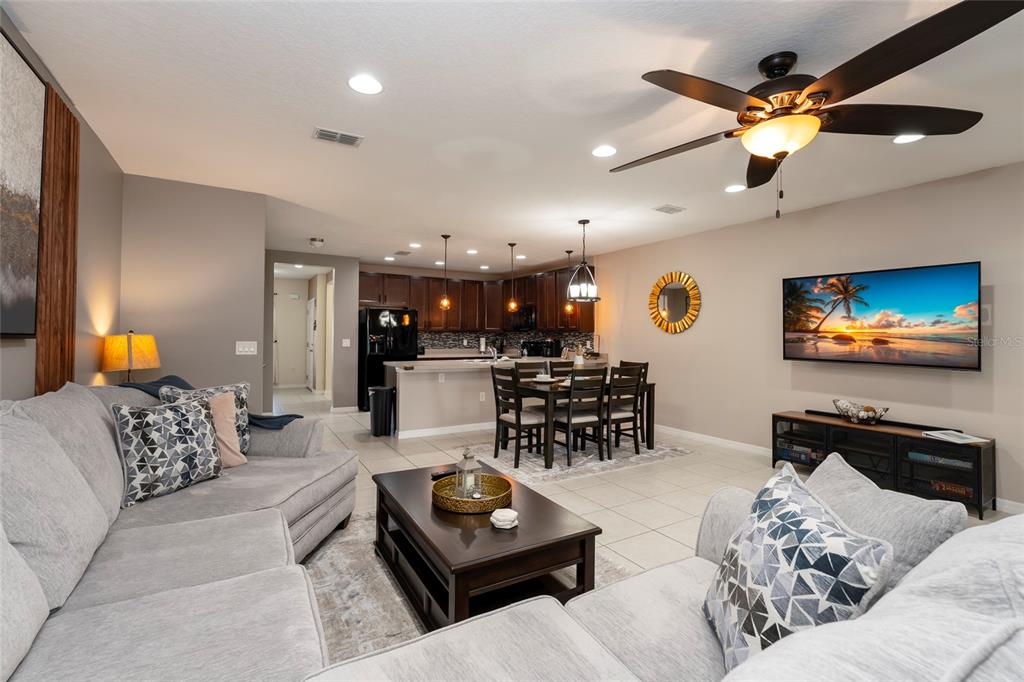 A living room with a grey sectional sofa, coffee table, and open kitchen with dining area — 269 PRIMROSE DRIVE, DAVENPORT, FL