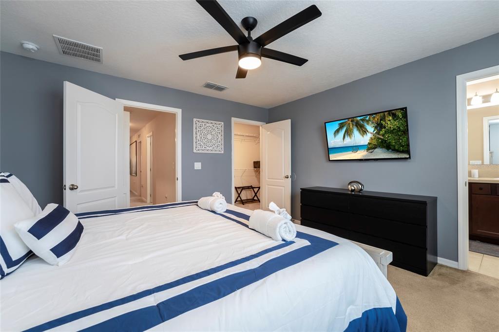 A bedroom features a bed with blue and white bedding, a ceiling fan, and a dresser — 269 PRIMROSE DRIVE, DAVENPORT, FL