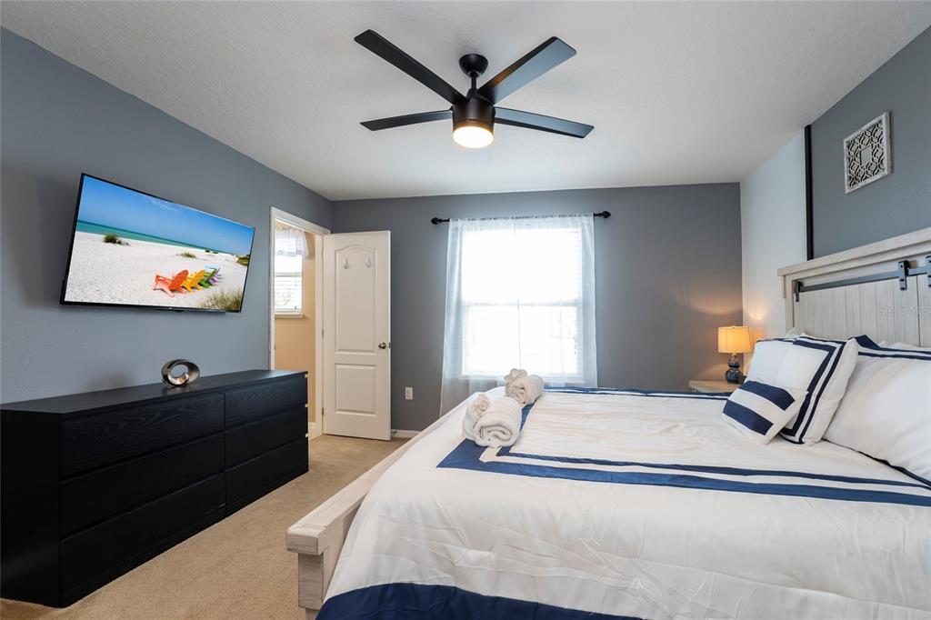 A bedroom features a bed with blue and white bedding, a black dresser, and a television — 269 PRIMROSE DRIVE, DAVENPORT, FL