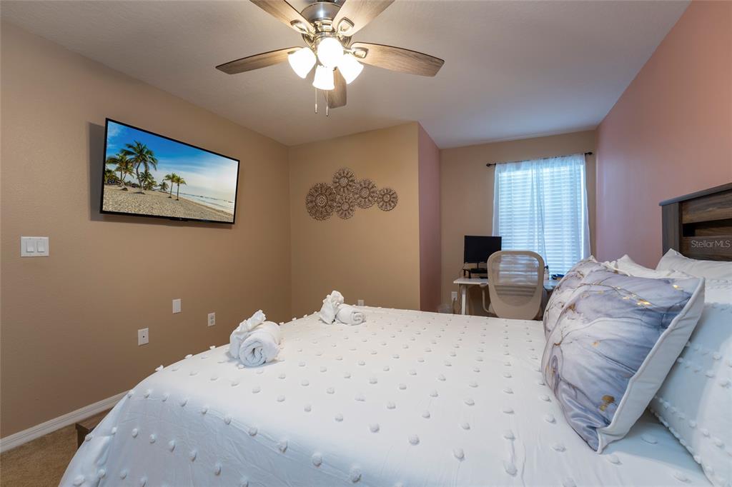 A bedroom features a bed with white bedding, a wall-mounted television, and a desk area — 269 PRIMROSE DRIVE, DAVENPORT, FL