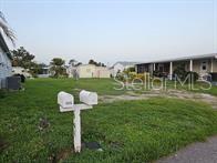 A grassy vacant lot sits between two mobile homes with a double mailbox in the foreground — 5672 HOLIDAY PARK BOULEVARD, NORTH PORT, FL