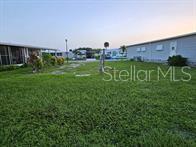 A grassy yard sits between two manufactured homes under a clear sky — 5672 HOLIDAY PARK BOULEVARD, NORTH PORT, FL
