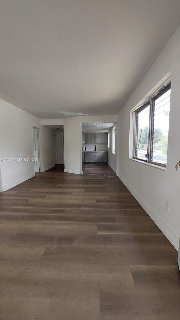An interior view shows a living area with wood-look flooring leading to a kitchen — 6151 SW 35th St # 1, Miramar FL 33023, MIRAMAR, FL