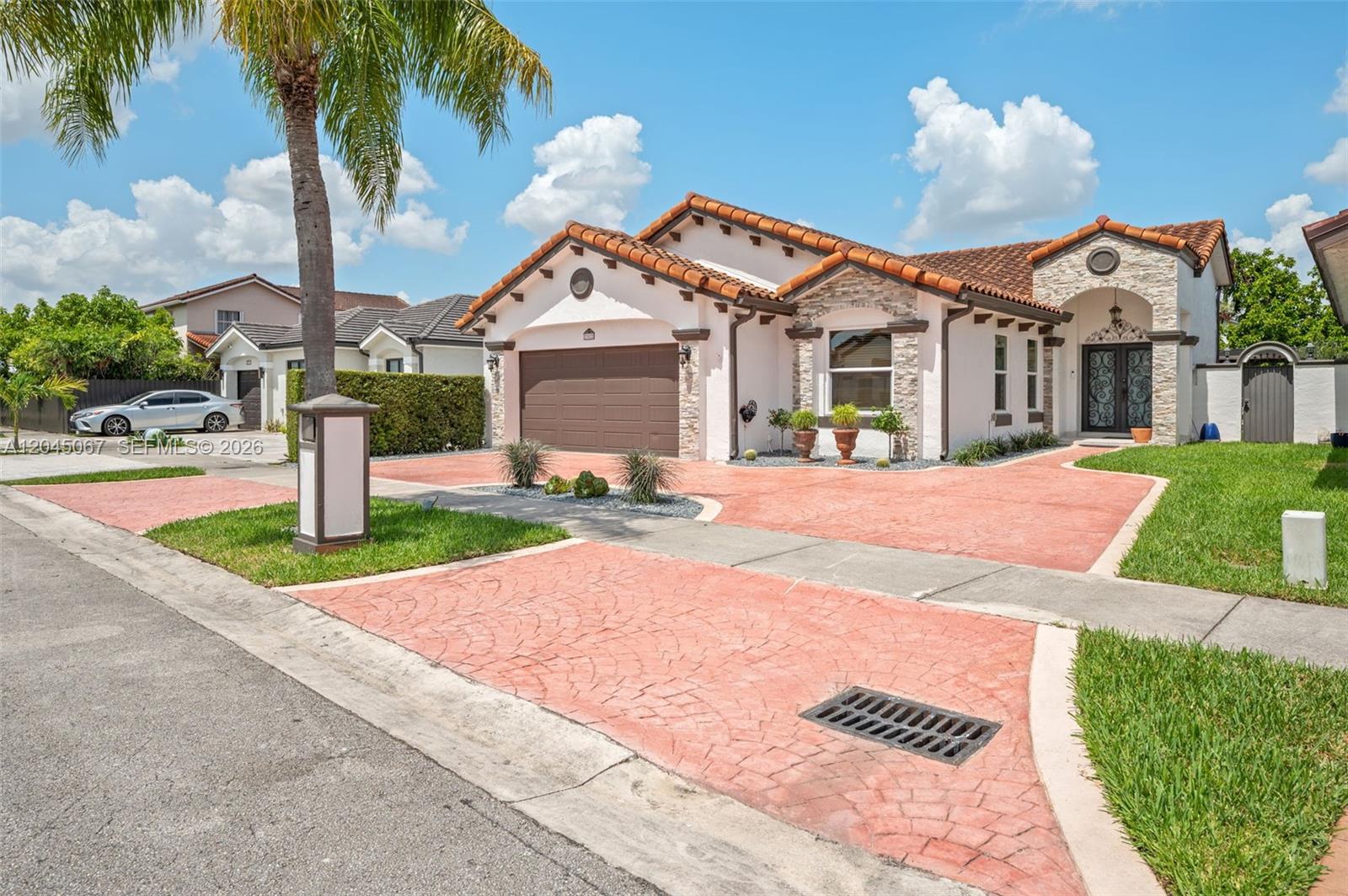 A single-story house with a terracotta tile roof, stone accents, and a red stamped driveway — 982 NW 133rd Ct # 0, Miami FL 33182, MIAMI, FL