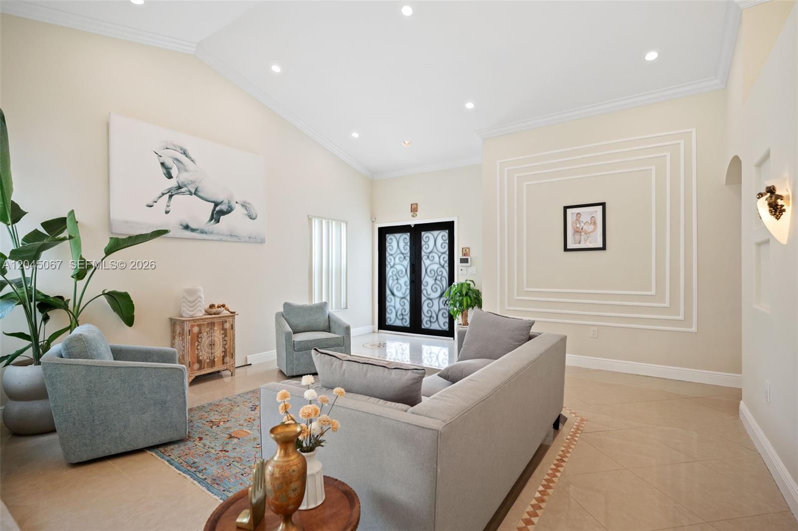A living room features light tile floors, a vaulted ceiling, and a decorative wall molding — 982 NW 133rd Ct # 0, Miami FL 33182, MIAMI, FL