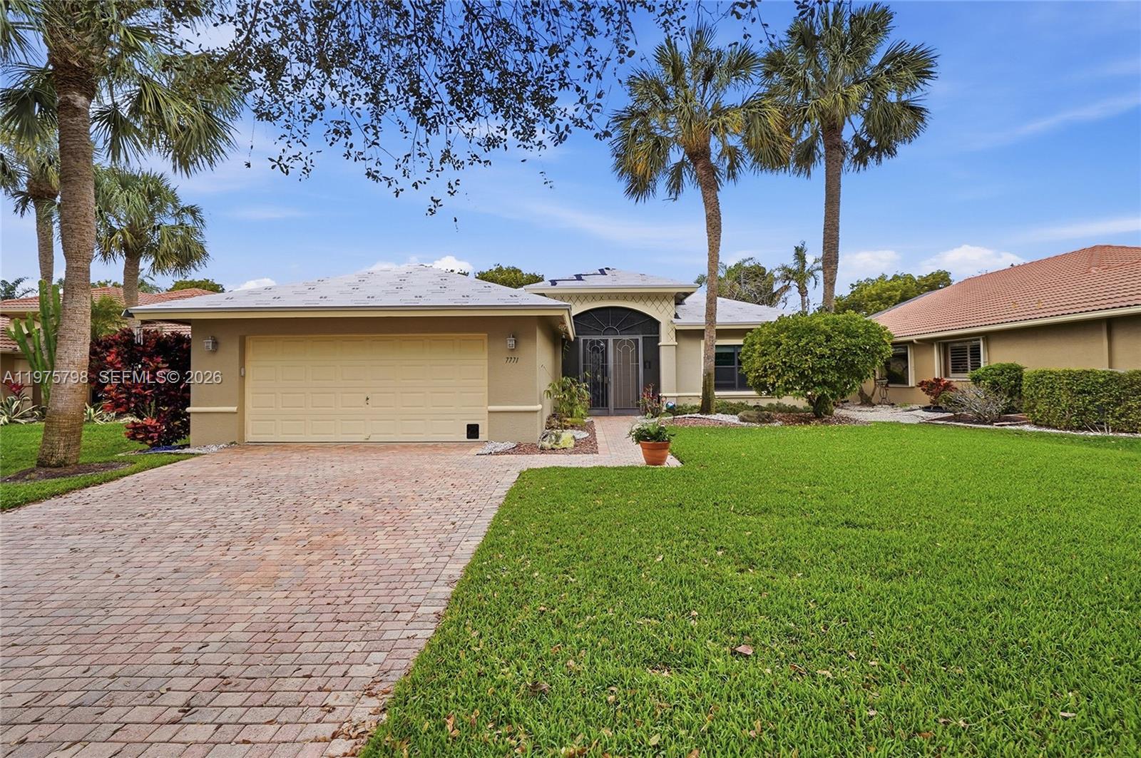 A single-story house with a beige exterior, a brick driveway, and a tiled roof — 7771 Via Grande, Boynton Beach FL 33437, BOYNTON BEACH, FL