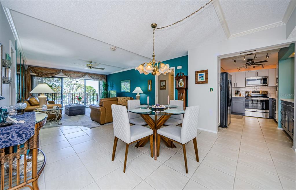 A dining area with a glass table and chairs sits adjacent to a living room — 2700 BAYSHORE BOULEVARD UNIT 11307, DUNEDIN, FL