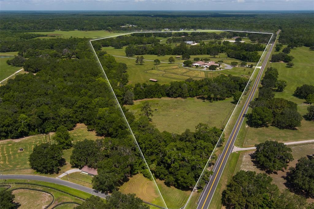 An aerial view shows a large, fenced rural property with a house and scattered trees — 9504 NW HWY 320, MICANOPY, FL