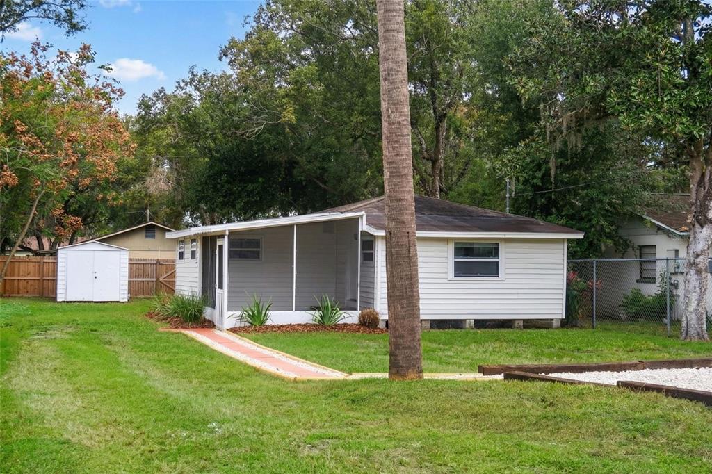 A white house with a screened-in porch, a storage shed, and a palm tree in back — 4829 6TH STREET, ZEPHYRHILLS, FL