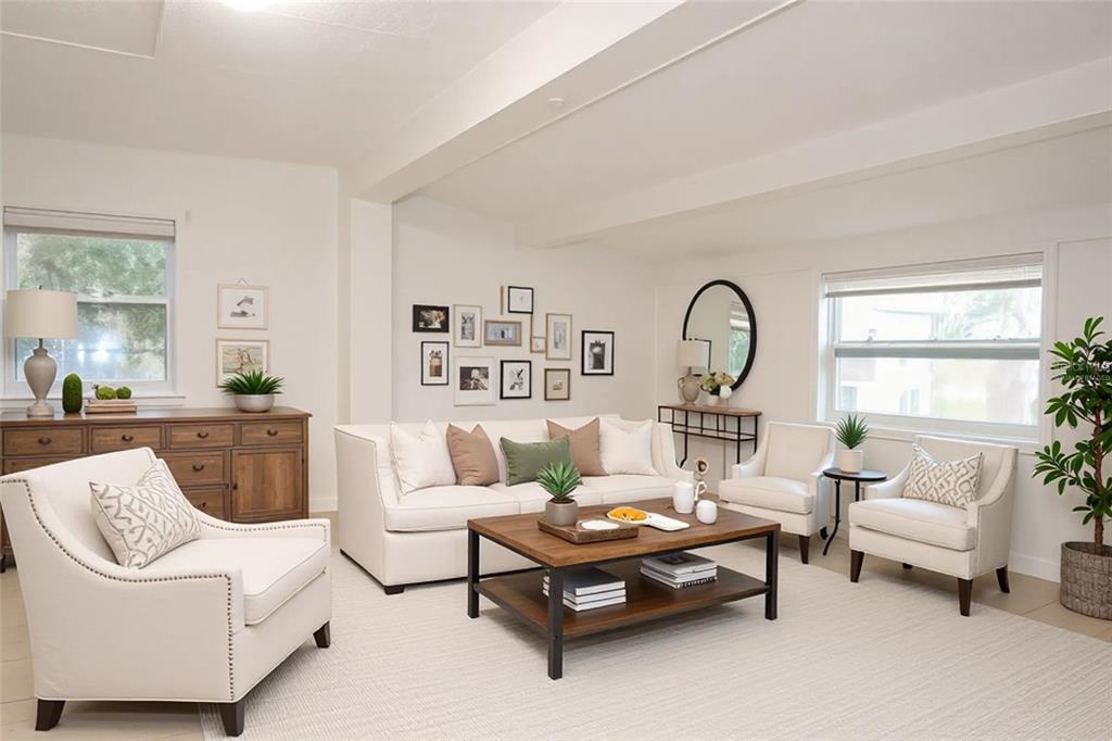 A bright living room features a white sofa, two armchairs, a wooden coffee table, and decor — 4829 6TH STREET, ZEPHYRHILLS, FL
