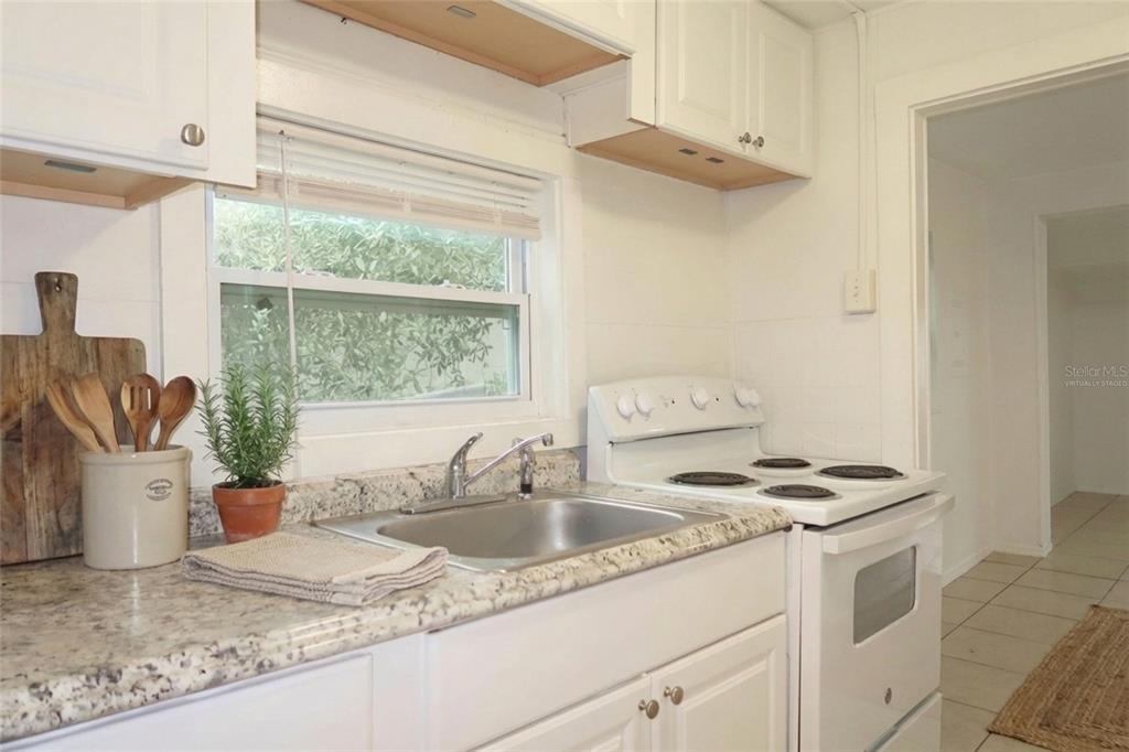 A kitchen features white cabinets, a granite countertop, a stainless steel sink, and an oven — 4829 6TH STREET, ZEPHYRHILLS, FL