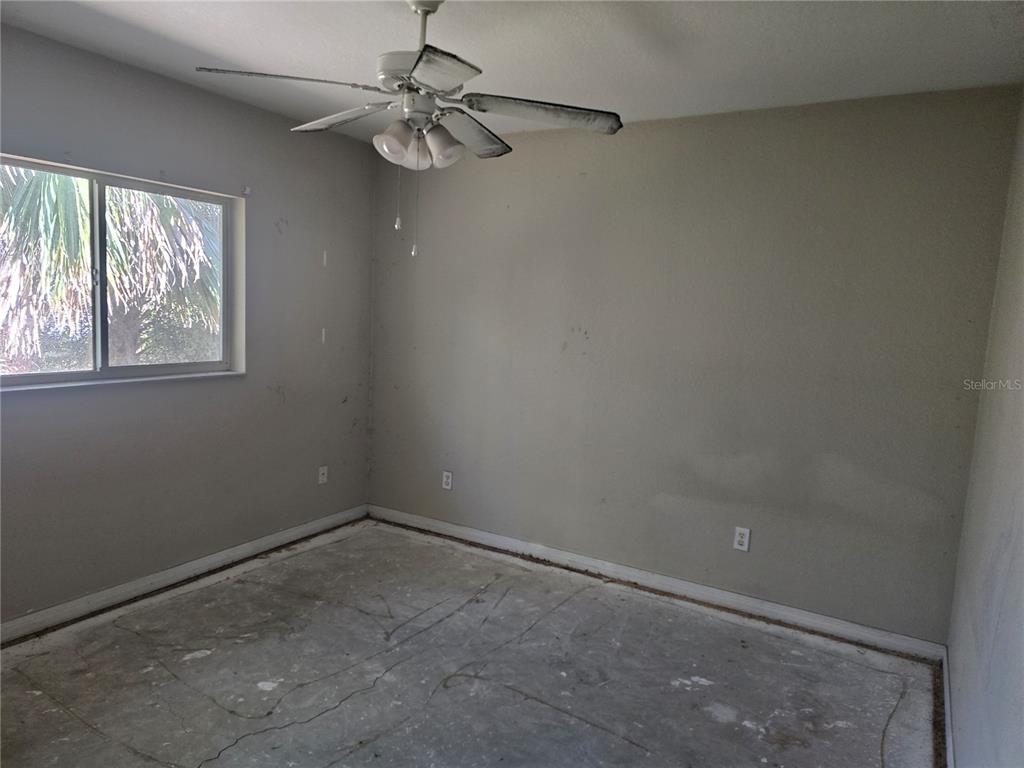 An empty bedroom features gray walls, a ceiling fan, and an unfinished concrete floor — 3828 TRENTON LANE, NORTH PORT, FL