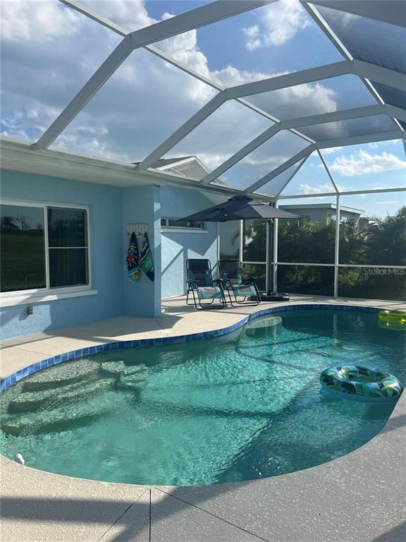 A screened-in swimming pool with patio furniture and a blue house exterior — 118 CADDY ROAD, ROTONDA WEST, FL