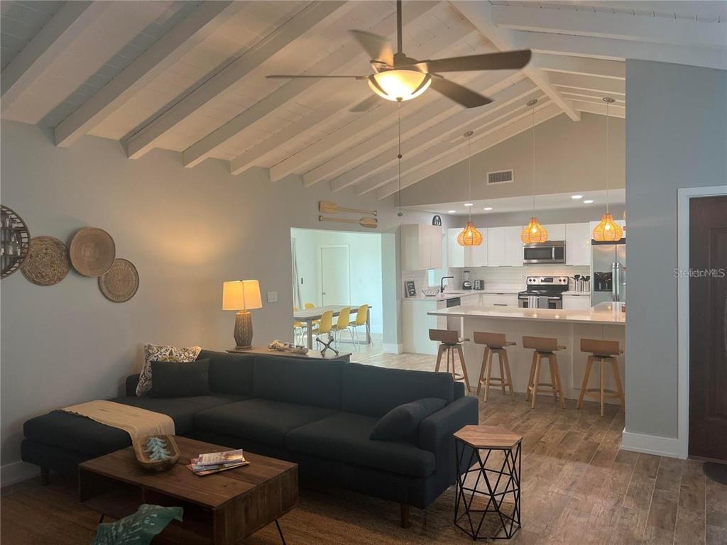 A living room with a vaulted ceiling opens into a kitchen with a breakfast bar — 118 CADDY ROAD, ROTONDA WEST, FL