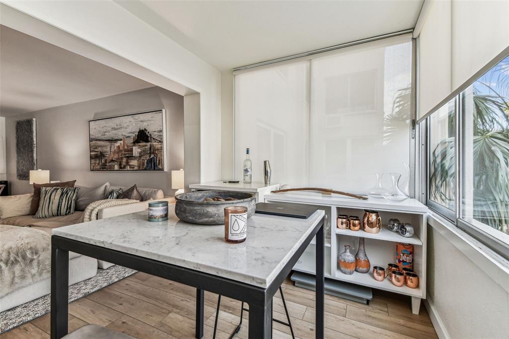 A dining area with a marble-topped table, open shelving, and a view into the living room — 620 EDGEWATER DRIVE UNIT 204, DUNEDIN, FL