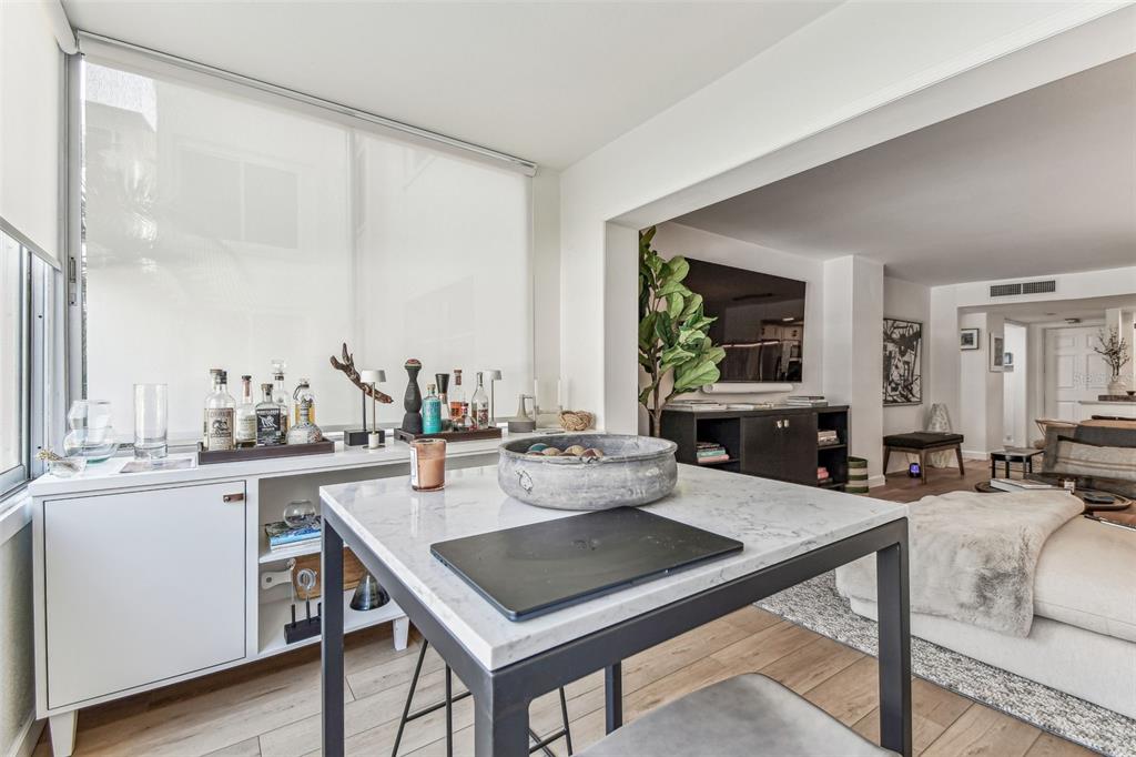 A modern room features a marble-topped table, a white sideboard bar, and a living area — 620 EDGEWATER DRIVE UNIT 204, DUNEDIN, FL