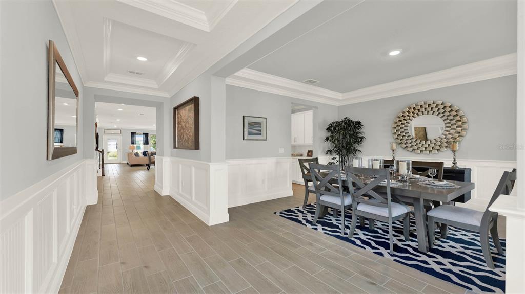 A dining room with wainscoting, a patterned rug, and a view into an adjacent living area — 11845 SHINE VIEW LANE, WINTER GARDEN, FL