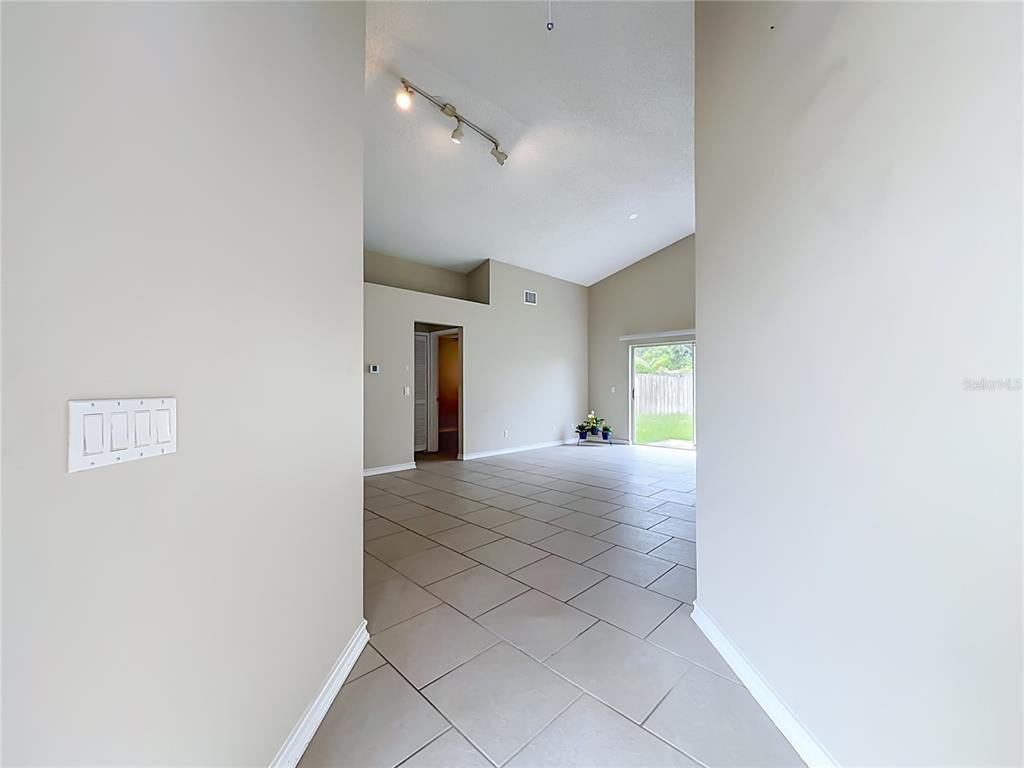 An interior view shows a tiled living area with vaulted ceilings and a sliding glass door — 930 RIVECON AVENUE, ORLANDO, FL