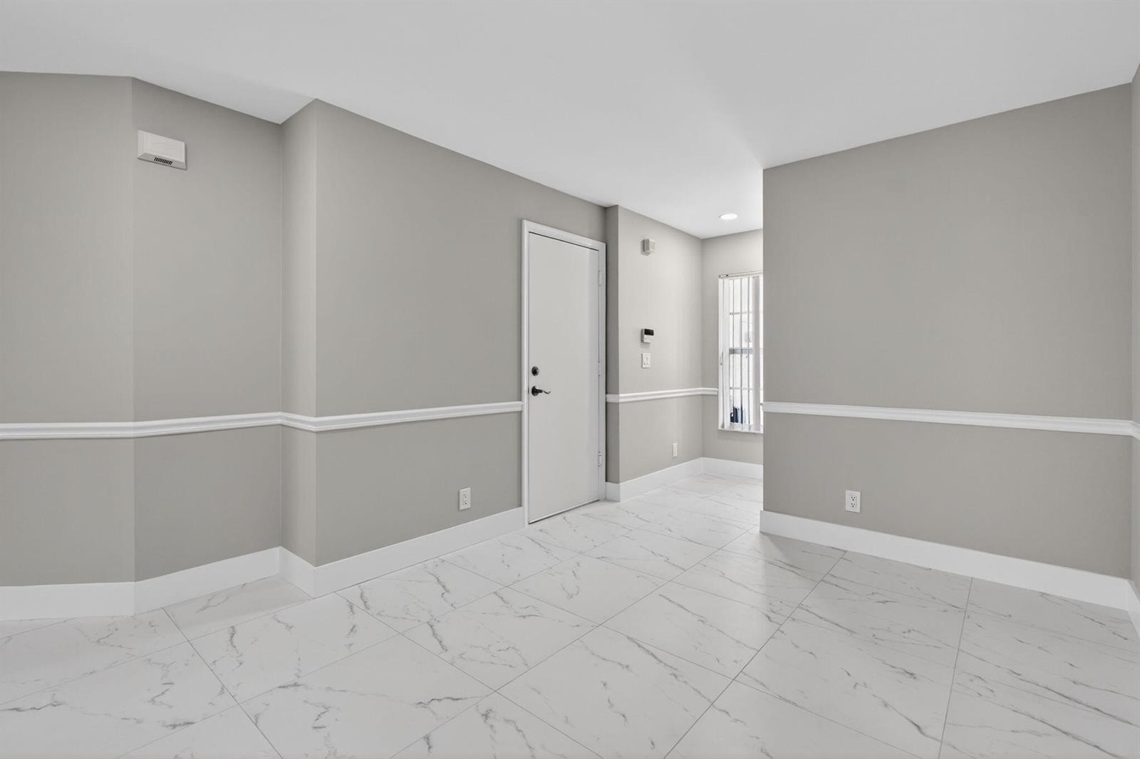 An empty room features gray walls, white chair rail molding, and white marble-patterned tile flooring — 106 Fox Meadow Run, Jupiter FL 33458, JUPITER, FL