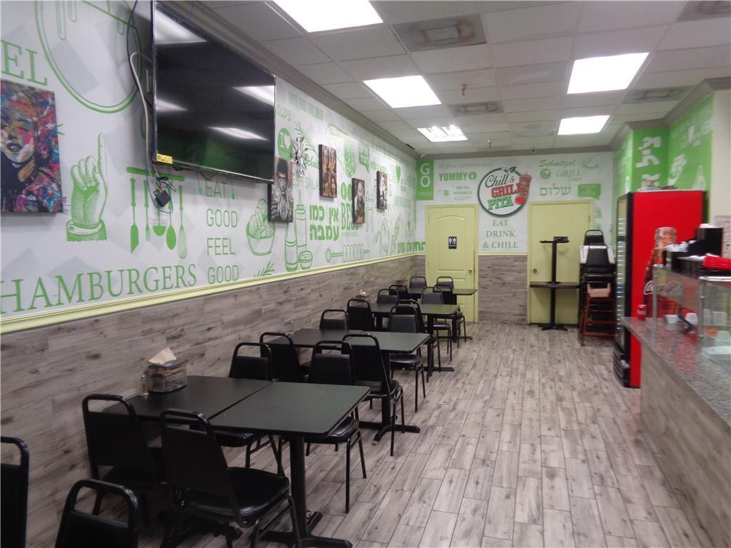 A restaurant dining area features black tables and chairs, wood-look flooring, and green-accented walls — 7158 N Beracasa Way, Boca Raton FL 33433, BOCA RATON, FL