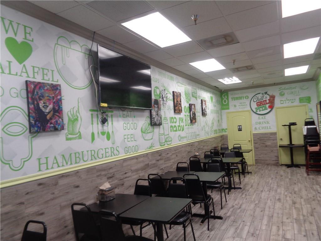 A restaurant interior features tables, chairs, a wall-mounted television, and decorative wall murals — 7158 N Beracasa Way, Boca Raton FL 33433, BOCA RATON, FL