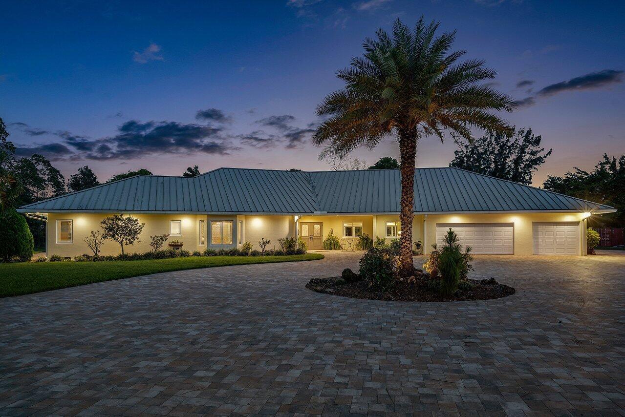 A single-story house with a metal roof and paved driveway at dusk — 6624 Dillman Road, FL 33413, FL