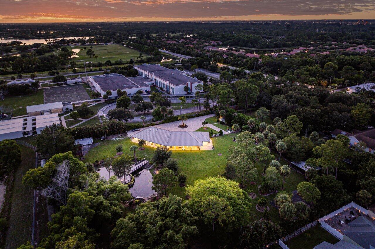 An aerial view shows a house with a lit patio, a pond, and nearby school buildings — 6624 Dillman Road, FL 33413, FL