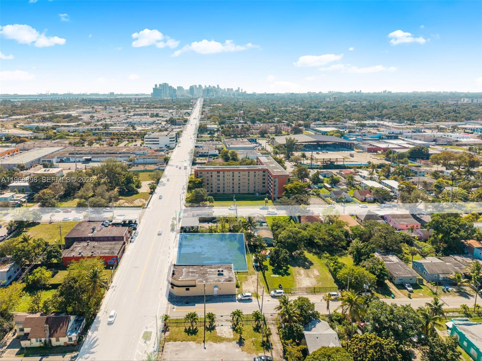 An aerial view shows a commercial building and parking lot along a long straight road — 7618 NE 2nd Ave, Miami FL 33138, MIAMI, FL