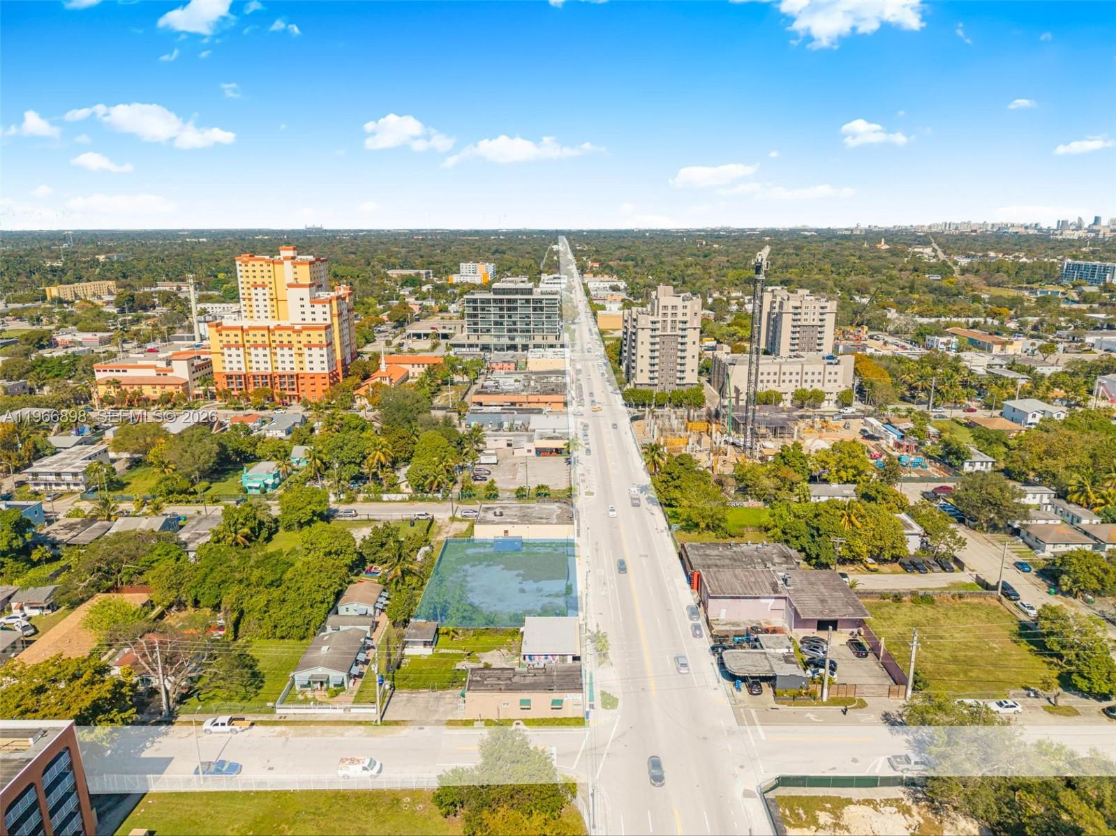 An aerial view shows a city street lined with buildings, construction sites, and surrounding trees — 7618 NE 2nd Ave, Miami FL 33138, MIAMI, FL