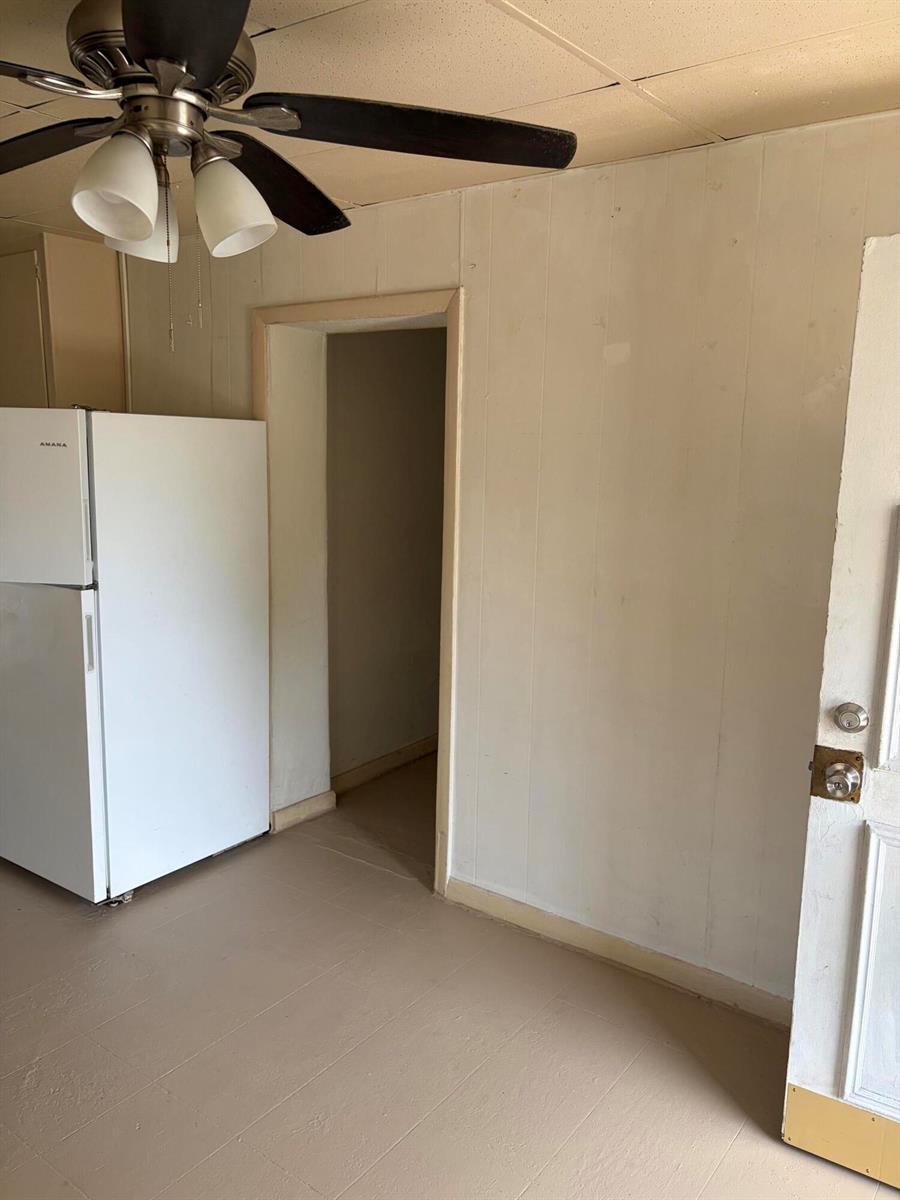 A kitchen features a white refrigerator, a ceiling fan, and paneled walls — 198 SE 4th Street, Delray Beach FL 33483, DELRAY BEACH, FL