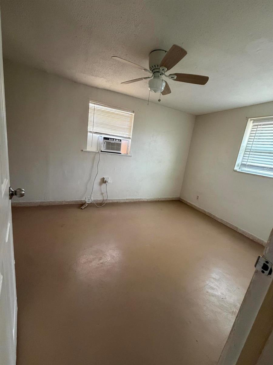 An empty bedroom features a ceiling fan, a window air conditioner, and light-colored flooring — 198 SE 4th Street, Delray Beach FL 33483, DELRAY BEACH, FL