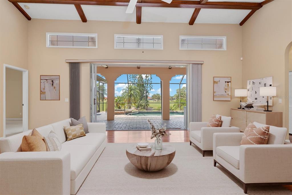 A living room with a vaulted ceiling, neutral furniture, and a view of a pool — 3825 BORDEAUX DRIVE, PUNTA GORDA, FL