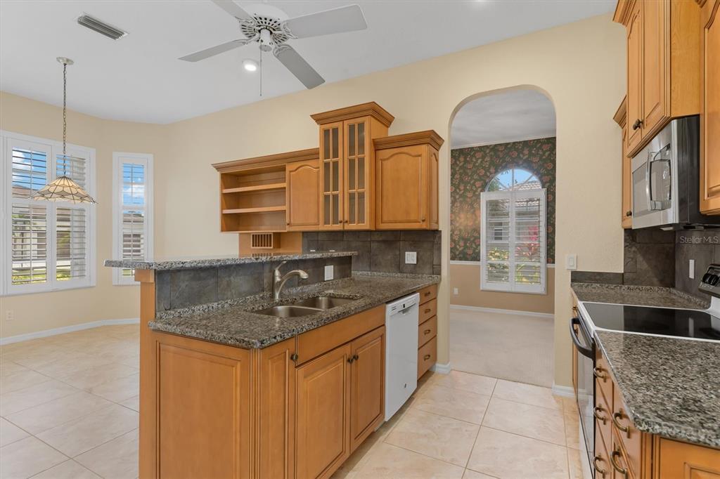 A kitchen with wood cabinets, granite countertops, a breakfast bar, and tile flooring — 3825 BORDEAUX DRIVE, PUNTA GORDA, FL