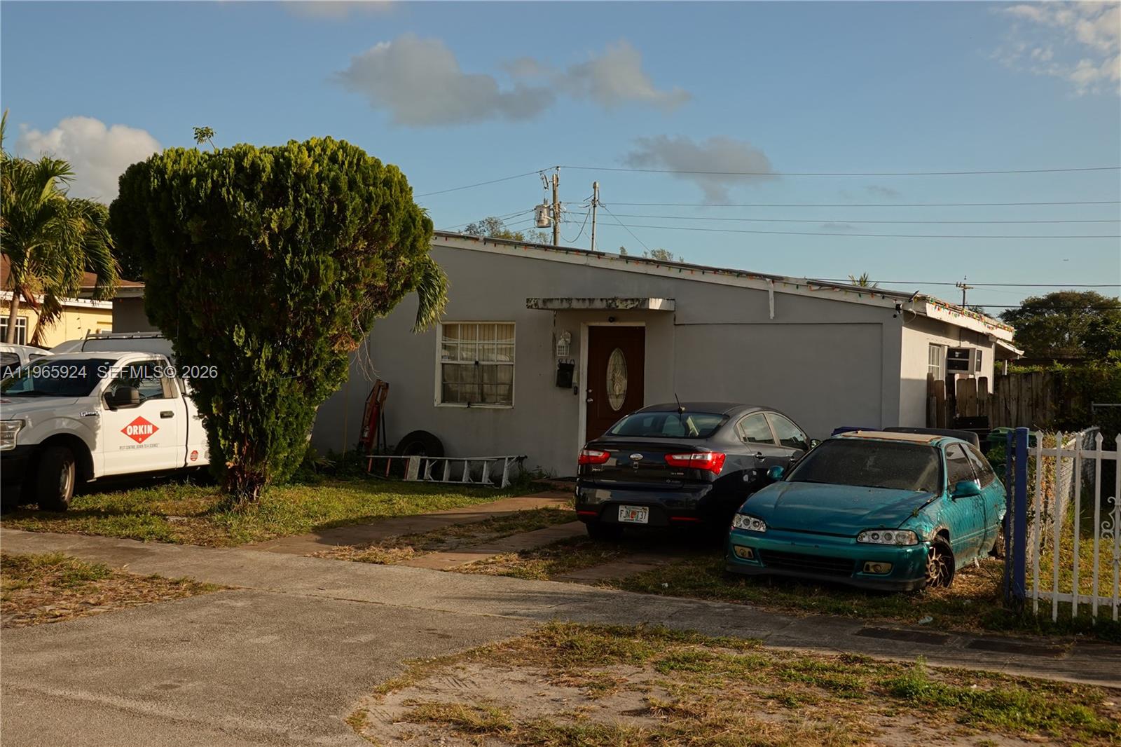 A single-story house with a grey exterior, a front yard, and three parked vehicles — 810 NW 84th Ter, Miami FL 33150, MIAMI, FL
