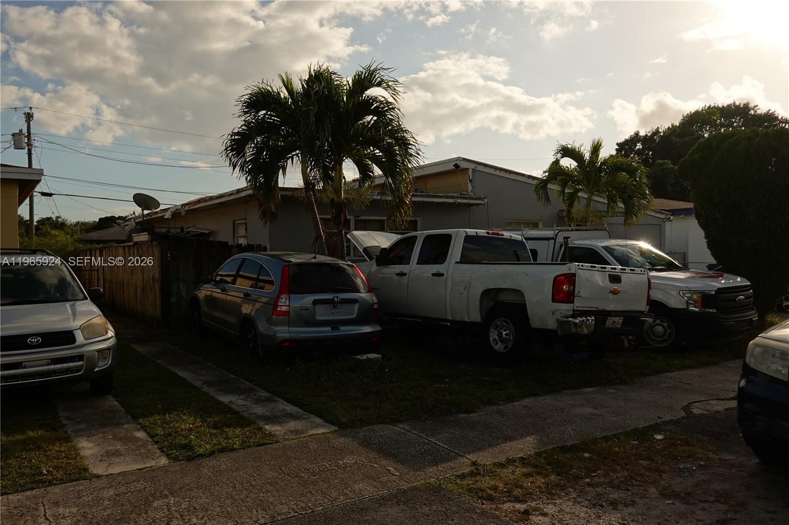 A residential property exterior features a driveway with several parked vehicles and palm trees — 810 NW 84th Ter, Miami FL 33150, MIAMI, FL