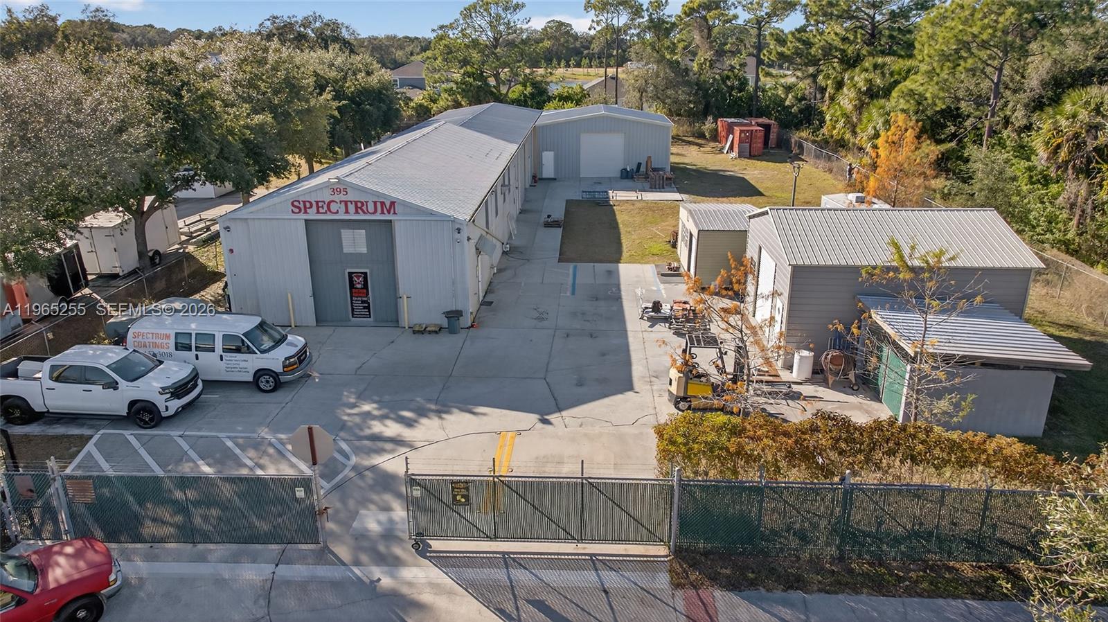 An aerial view shows a commercial property with metal warehouse buildings, a paved lot, and fencing — 395 Williams Point Blvd, Cocoa FL 32927, COCOA, FL