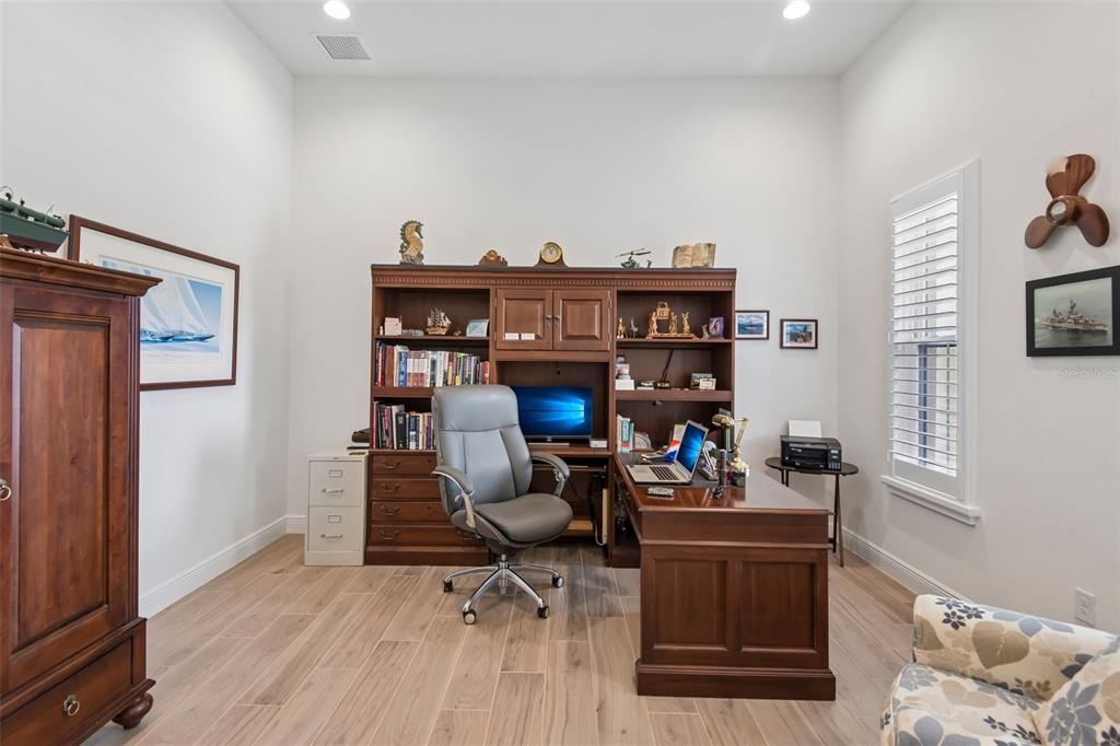 A home office features a large wooden desk, matching hutch, grey chair, and light wood flooring — 14537 SWISS BRIDGE DRIVE, LITHIA, FL