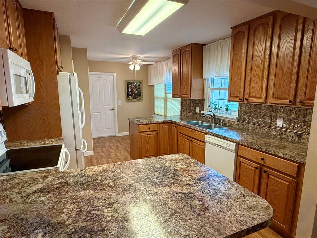 A dining room with a wooden table, chairs, and a ceiling fan, opening to a kitchen — 1122 STILLWATER DRIVE, DELAND, FL
