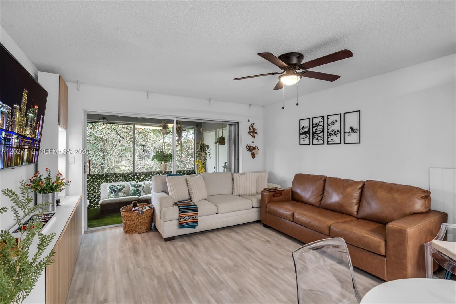 A living room features a brown leather sofa, a cream couch, and a sliding glass door — 420 NW 70th Ave # 228, Plantation FL 33317, PLANTATION, FL
