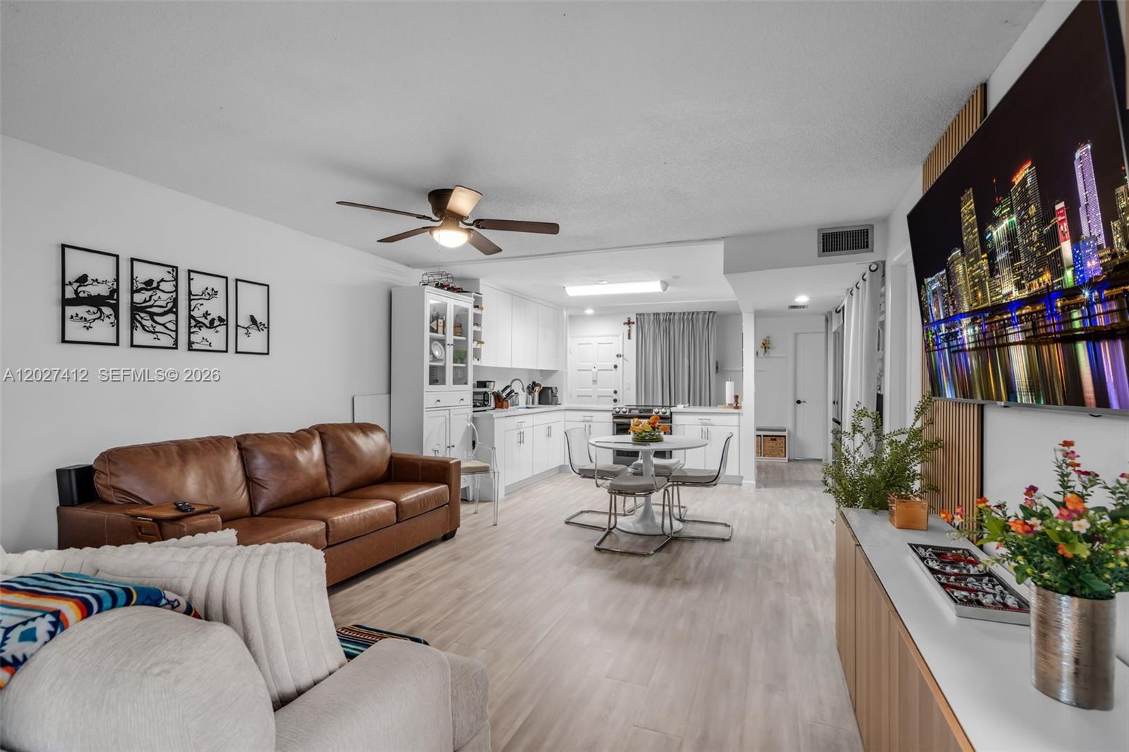 An open-concept living room and kitchen feature a brown leather sofa, dining set, and television — 420 NW 70th Ave # 228, Plantation FL 33317, PLANTATION, FL