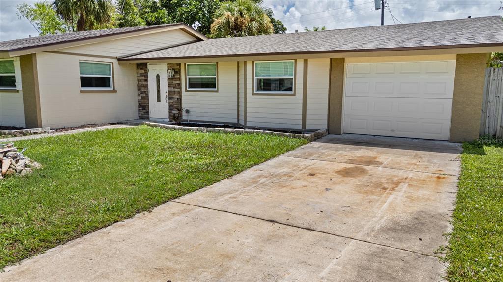 A single-story house with a beige exterior, a white front door, and a concrete driveway — 3831 118TH STREET W, BRADENTON, FL