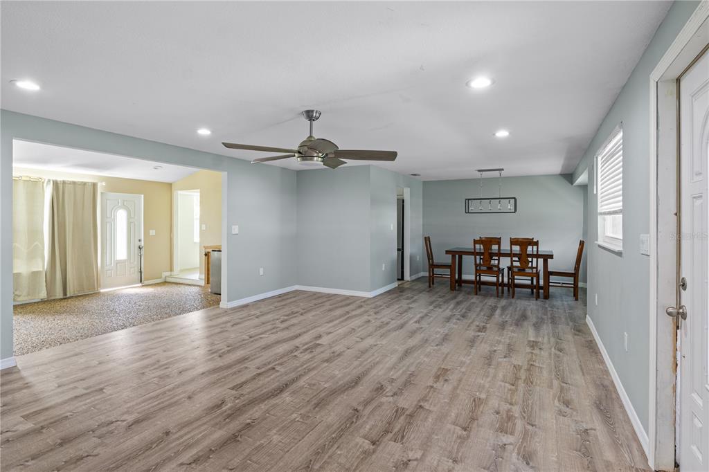 A spacious living and dining area with light wood-look flooring and a ceiling fan — 3831 118TH STREET W, BRADENTON, FL