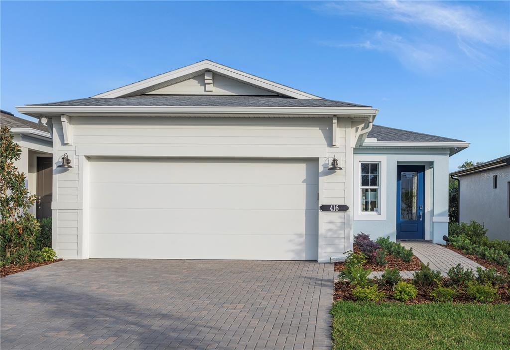 A single-story house features a white garage door, light blue siding, and a blue door — 427 VERONA WAY, LADY LAKE, FL
