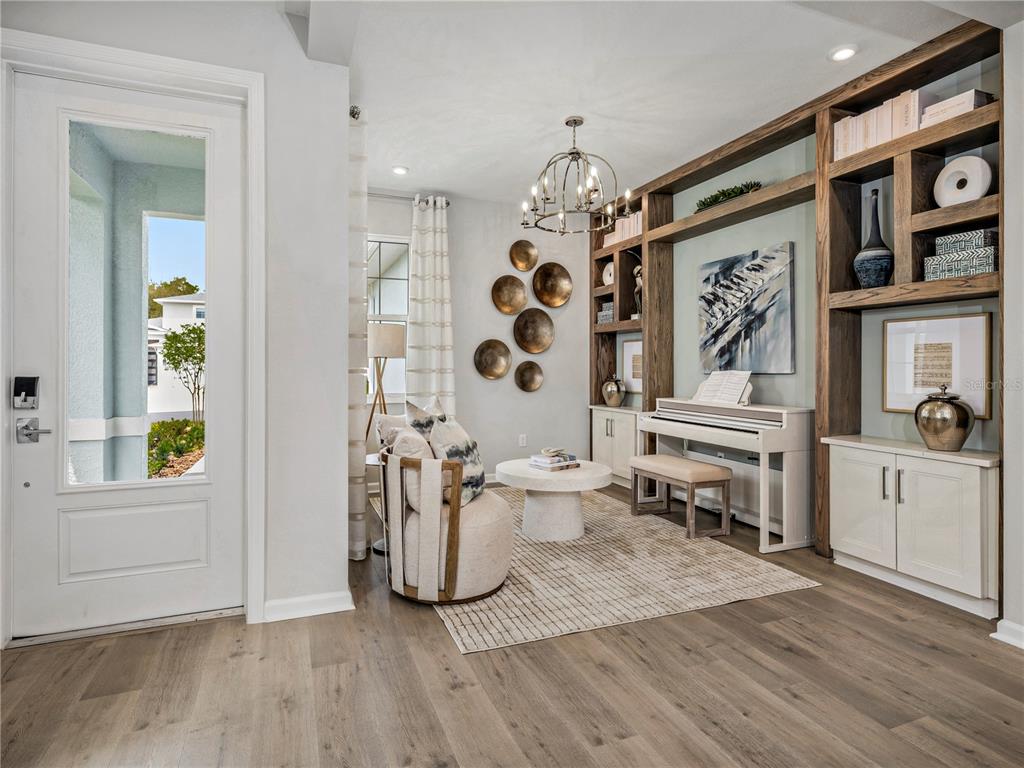 A living room features a white piano, built-in wooden shelving, and a round accent chair — 427 VERONA WAY, LADY LAKE, FL
