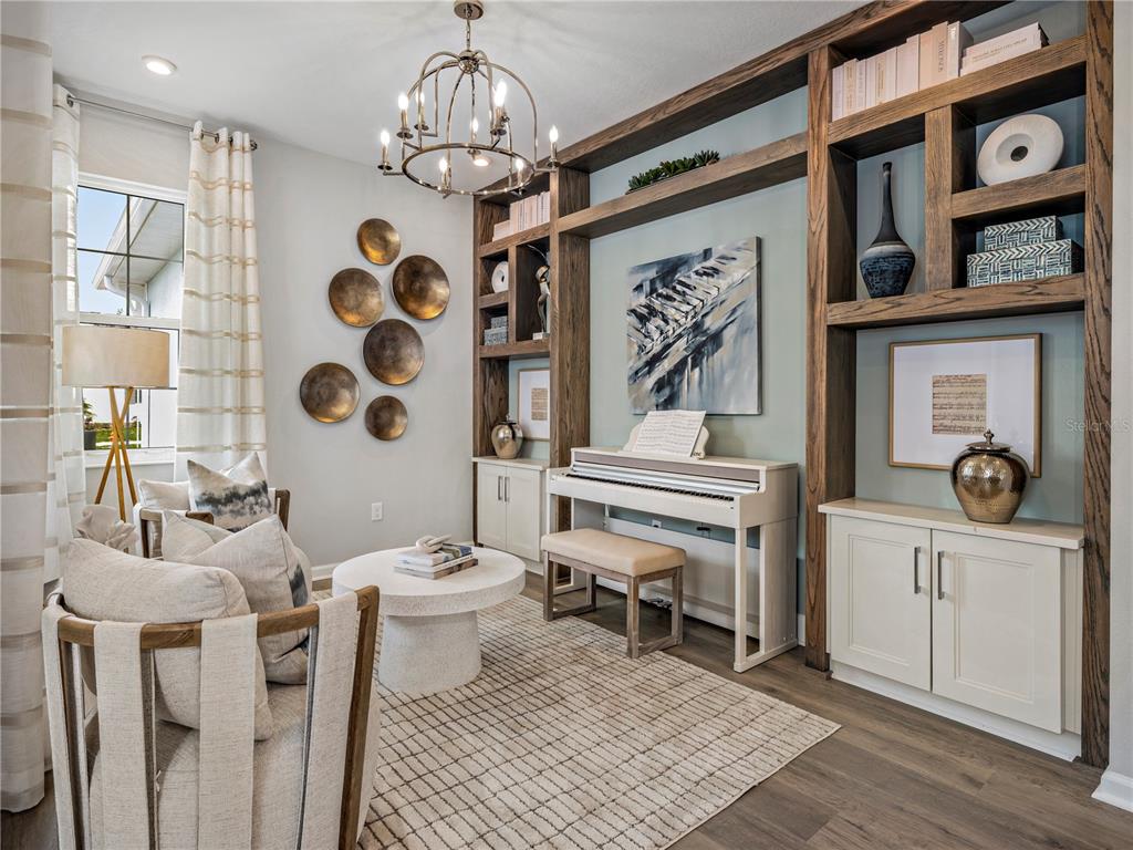 A living room features a piano, built-in wooden shelving, a chandelier, and two armchairs — 427 VERONA WAY, LADY LAKE, FL