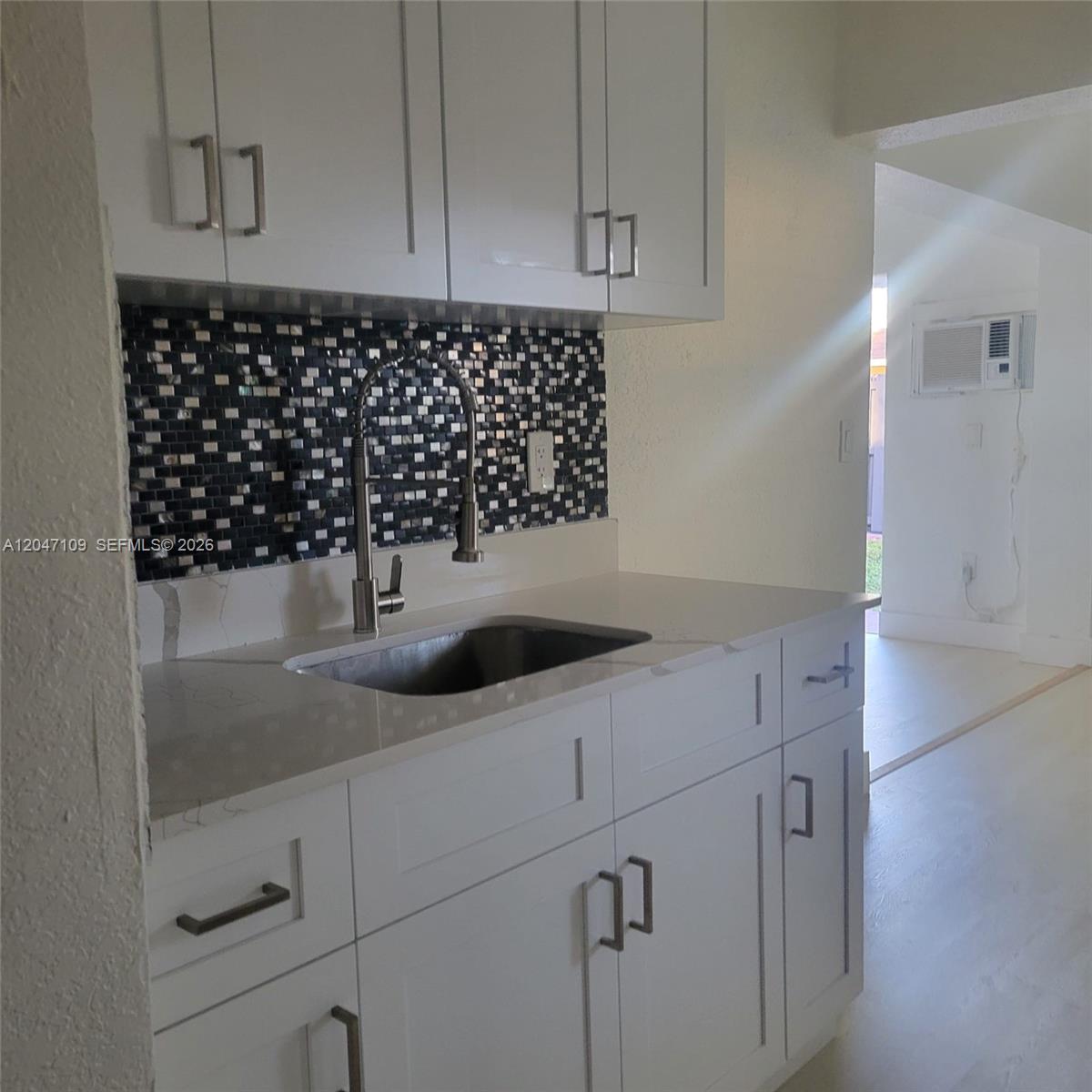 A kitchen features white cabinets, a quartz countertop, and a dark mosaic tile backsplash — 715 SW 6th St # 2, Dania Beach FL 33004, DANIA BEACH, FL