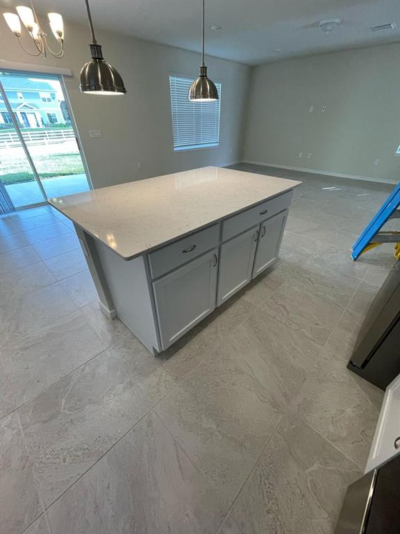 A kitchen island with white cabinets and a light-colored countertop sits on tiled flooring — 1926 ENCHANTING COURT, DAVENPORT, FL
